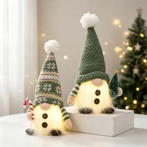 Detailed view of two lighted green knitted Christmas gnomes on white wood block