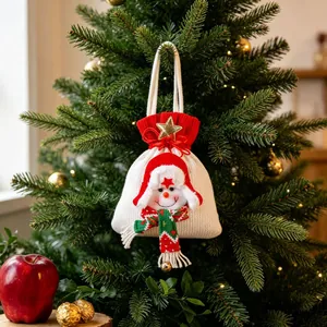 Feestelijke gebreide sneeuwpop kerstcadeauzak hangend aan een versierde kerstboom