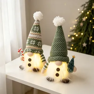 Close-up of two green knitted Christmas gnomes with warm glowing beards on table