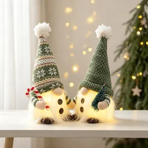 Close-up of glowing Christmas gnomes with green knitted hats and festive warm LED lights
