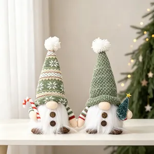 Close-up detail of two green knitted Christmas gnomes with white beards on a table