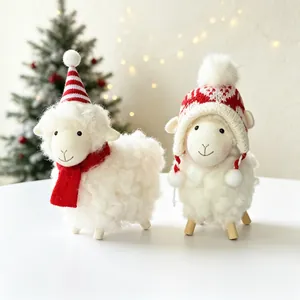 Deux mignons moutons de Noël en peluche avec bonnets rouges sur un fond de table blanc