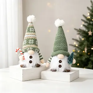 Close-up of green knitted Christmas gnomes with warm LED glow and candy cane detail