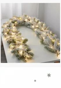 Macro detail of flocked Christmas garland with warm LED fairy lights on white surface