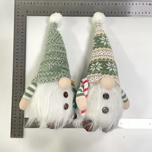 Detailed view of two green knitted Christmas gnomes with LED lights and ruler for size