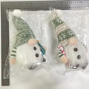 Pair of green knitted Christmas gnomes in plastic packaging with ruler for size reference