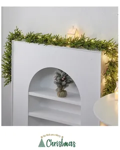 Festive artificial Christmas garland with warm LED lights draped over a fireplace