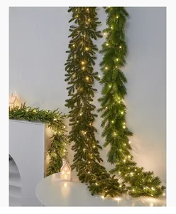 Close-up of lighted artificial Christmas pine garland draped over a white holiday scene