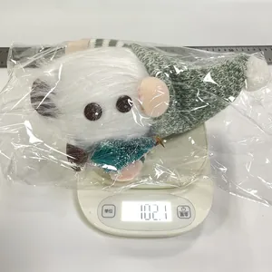 Detailed view of a green knitted Christmas gnome plush weighing 102.1g on a digital scale