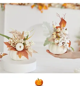 Detailansicht eines weißen künstlichen Kürbisses mit Ahornblättern und Beeren für Halloween-Deko.