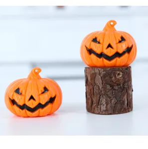 Gros plan de deux mini lanternes de citrouille d'Halloween sur un socle en bois brut.
