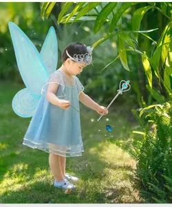 Bambina con ali di fata a farfalla blu con set di tiara e bacchetta magica nel giardino
