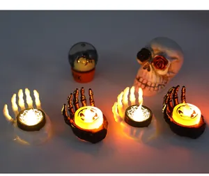 Detailed view of four glowing skeleton hand LED candles for Halloween decor.