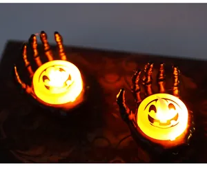 Close-up of Halloween skeleton hand holding a glowing orange pumpkin candle LED light ornament