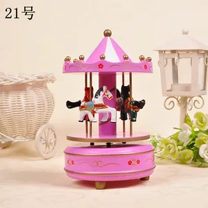 Close-up detail showing carousel horses and striped roof on a pink decorative music box.