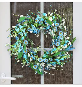 Vista detallada de una corona de flores artificiales azules y blancas en una puerta