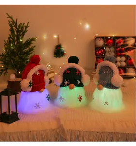 Detail of three glowing Christmas gnome dolls with knitted hats and LED beards on white cloth