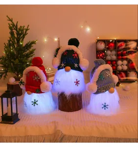 Close-up of three glowing plush Christmas gnomes with knitted hats in a warm festive scene