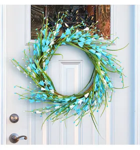 Detalle de una corona de bayas de primavera con flores azules y blancas en la puerta