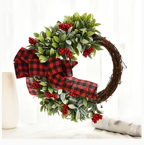Elegant handmade Christmas wreath featuring red berries, green leaves and a plaid bow