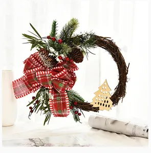 Close-up of a rustic Christmas grapevine wreath with red plaid bow and pine cones.