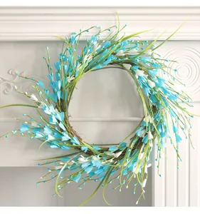 Detalle de una corona floral decorativa con flores azules y blancas sobre base de ramitas.
