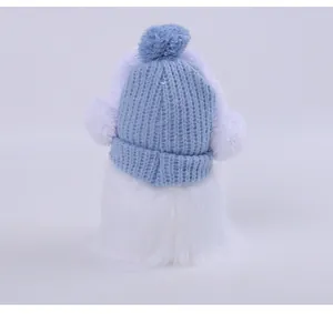 Close-up detail of a Christmas gnome doll wearing a blue knitted hat with white pompoms