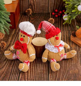 Detail view of two gingerbread man plush dolls in festive Christmas costumes on wood.