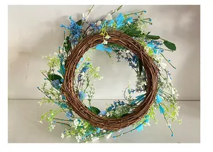 Elegante corona de flores y bayas azules y blancas sobre anillo de vid seca natural