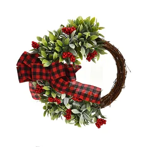 Festive Christmas wreath featuring red berries buffalo plaid bow and green leaves
