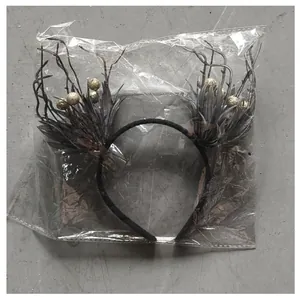 Detailed view of a dark Halloween antler branch headband with gold beads in clear plastic packaging