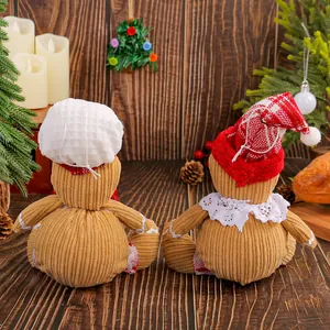 Festive pair of plush gingerbread man dolls wearing holiday hats on a wooden table.
