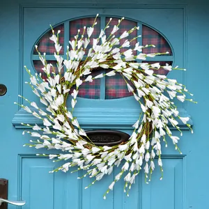 Corona decorativa de bayas blancas en una puerta azul para decoración festiva hogar