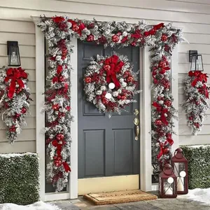 Set festivo de corona y guirnalda de Navidad nevada con adornos rojos en puerta principal