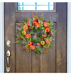 Handcrafted autumn wreath with pumpkins and roses hanging on a wooden front door