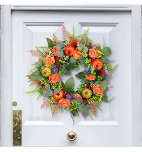 Autumn wreath with pumpkins and orange roses displayed on a white front door