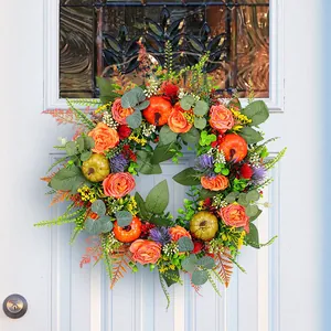 Vibrant autumn wreath with orange roses and pumpkins hanging on a white front door