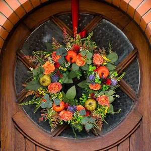 Vibrant autumn wreath with faux pumpkins and orange roses for Thanksgiving door decor.