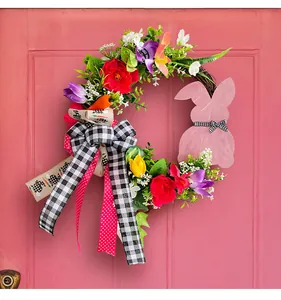 Detailansicht des bunten Osterkranzes mit rosa Holzhasen und karierter Schleife am Band.