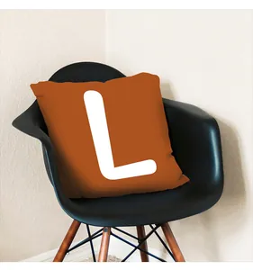 Detailed view of an orange harvest festival cushion cover featuring a white letter L