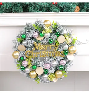 Detail view of snowy Christmas wreath with colorful baubles and gold Merry Christmas sign