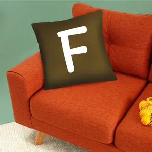 Decorative brown pillow cover with a white letter F on an orange sofa