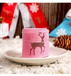 Detailaufnahme einer rosa Weihnachtsschleife mit Glitzer-Rentier-Design auf einem weißen Teller