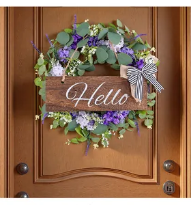 Dettaglio ghirlanda di eucalipto con fiori viola e targa in legno Hello per porta.