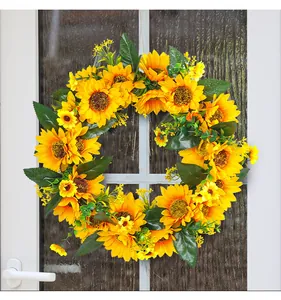 Couronne de tournesols artificiels jaunes suspendue sur une porte vitrée
