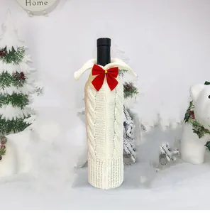Funda de punto blanca para botella de vino de Navidad con lazo rojo y fondo nevado