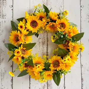 Couronne de tournesols artificiels sur fond de bois blanc pour décoration de porte