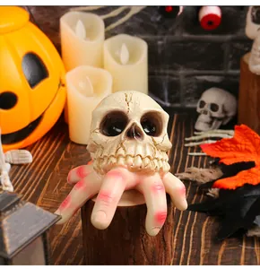 Λεπτομερής άποψη τρομακτικού κρανίου Halloween από ρητίνη σε διακοσμητική ξύλινη βάση με χέρια