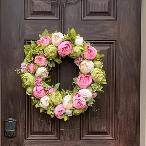 Bella ghirlanda di peonie artificiali primaverili appesa a una porta di legno scuro