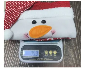 Détail d'un sac cadeau tricoté bonhomme de neige de Noël pesant 85,8 g sur balance.